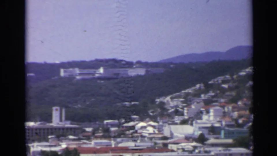 1967 U.S. Virgin Islands view of red-roofed buildings, waterfront structures and a large hillside complex in soft 8mm color.
