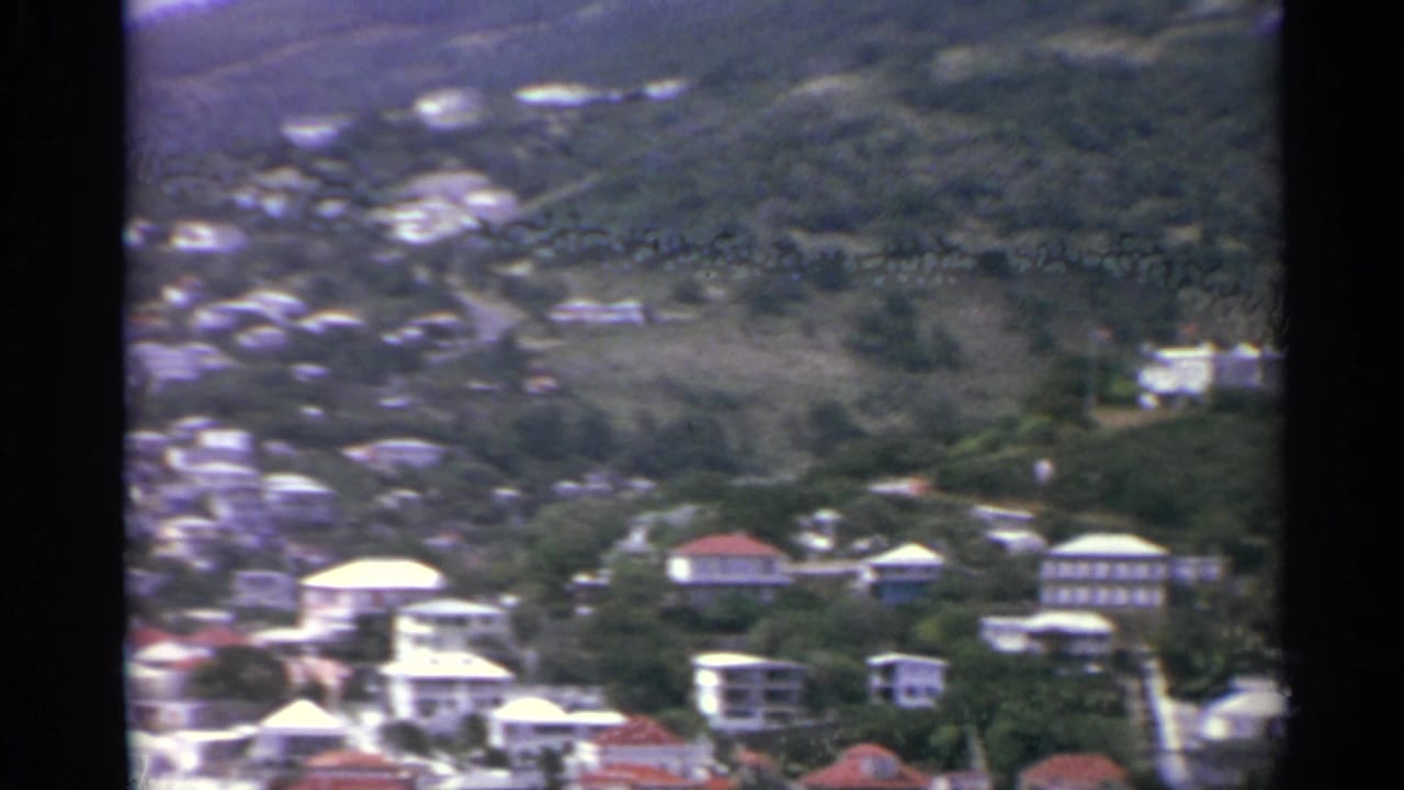 Green hillside with scattered buildings and winding roads.