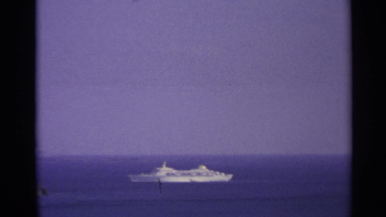 Distant white passenger ship at sea in the US Virgin Islands, framed by 8mm film edges and a purple-blue horizon.