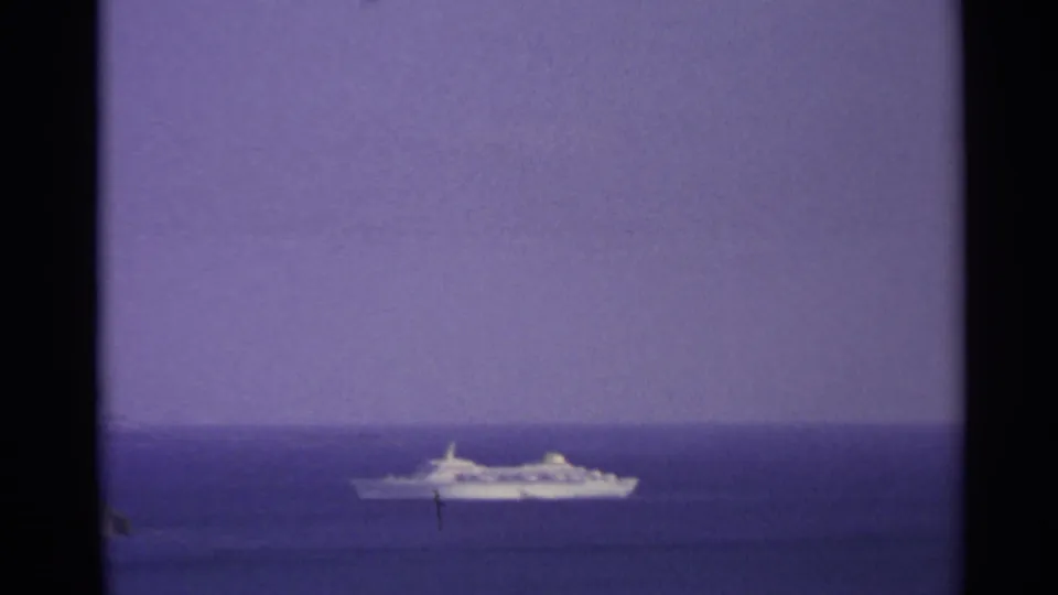 Distant white passenger ship at sea in the US Virgin Islands, framed by 8mm film edges and a purple-blue horizon.