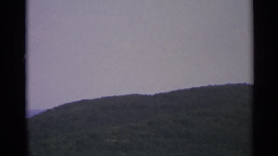 1967 US Virgin Islands frame with a forested coastal ridge under a pale sky, partially divided by contact-sheet borders.