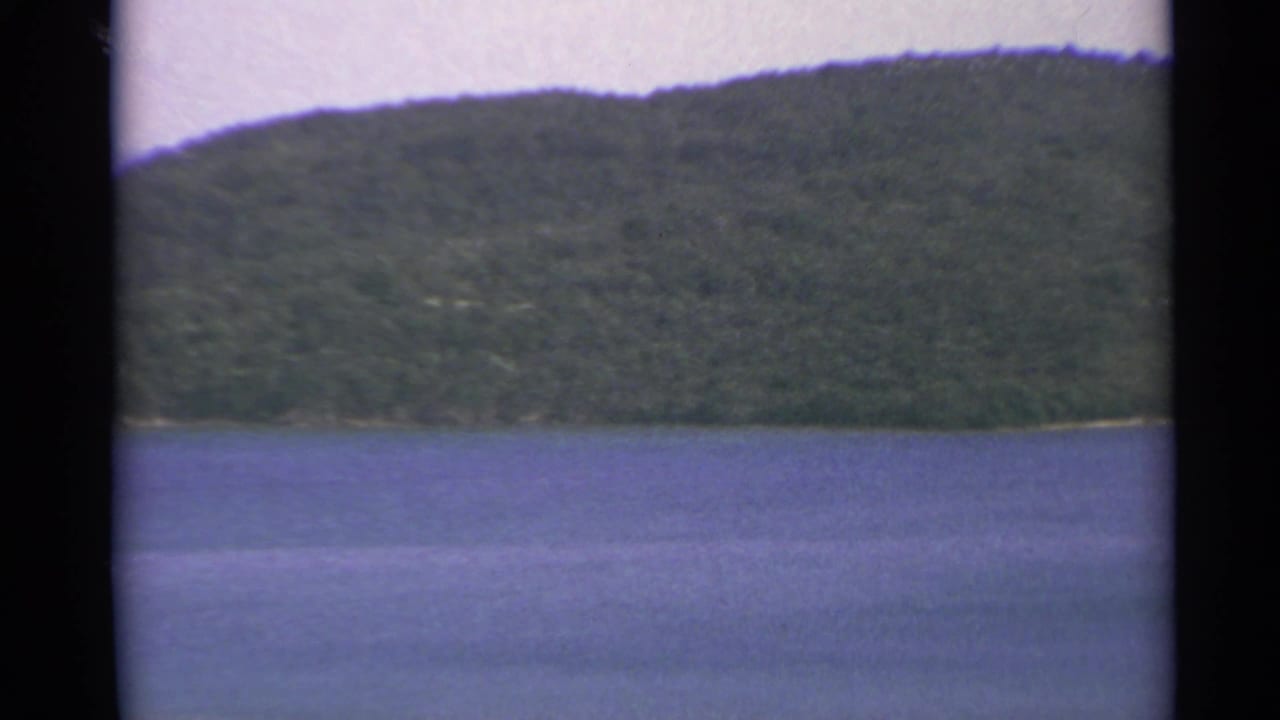 Blue water below a forested hillside with black 8mm frame borders.
