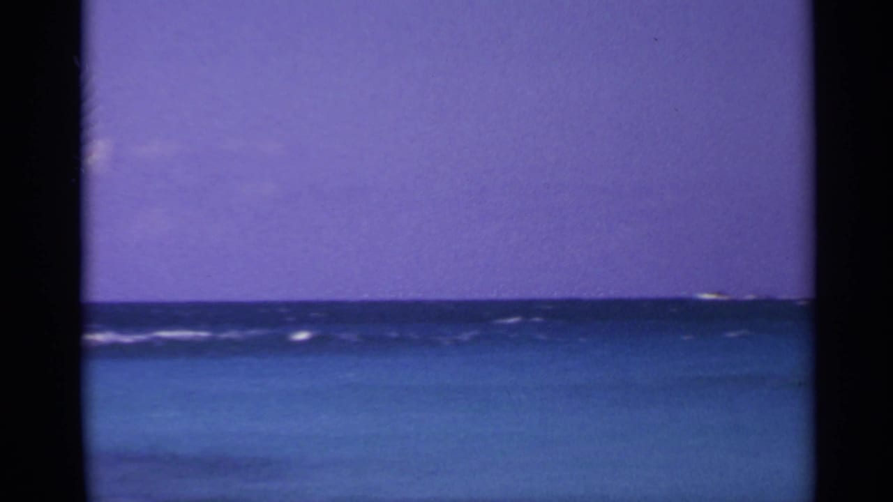 Blue ocean horizon beneath a purple sky with dark film-frame borders.