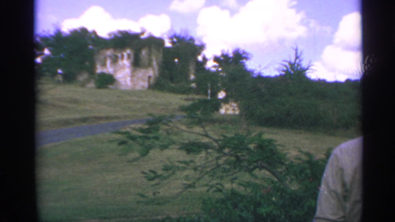Hillside ruins and path with a partial person at the right edge of the frame.