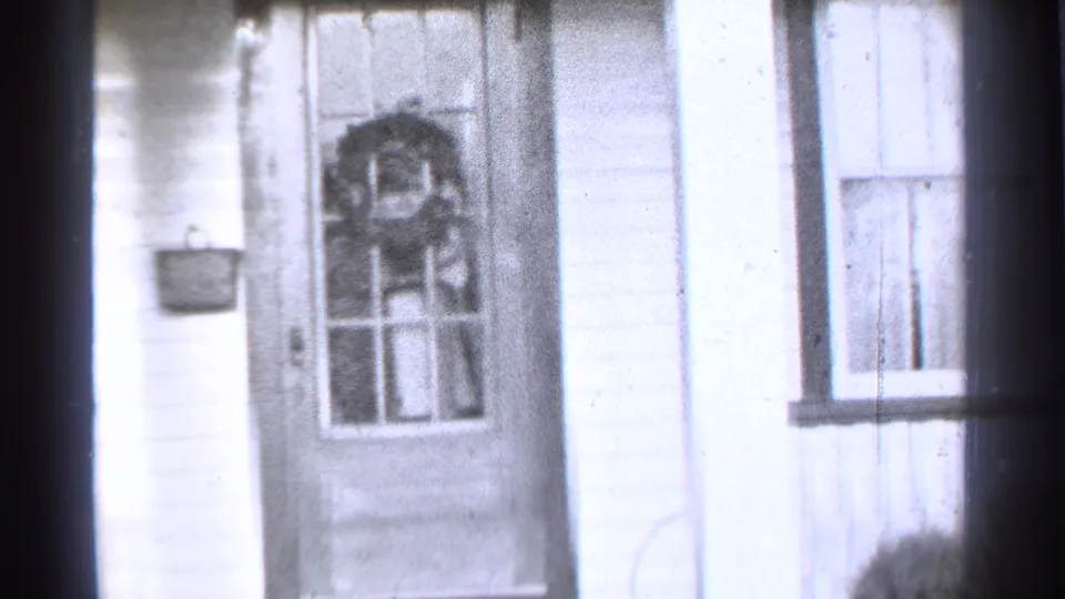 1939 Danielson, Connecticut home-movie frame showing a white-sided house entrance with a wreath on the front door and a window beside it.
