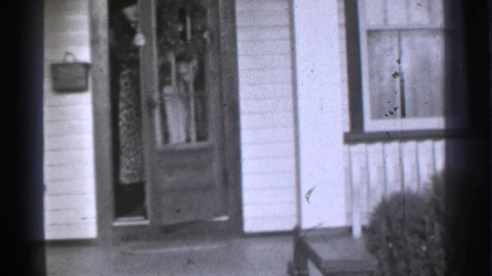 1939 Danielson, Connecticut frame of a residential entrance with door, window, porch edge, and a small bush near the right side.