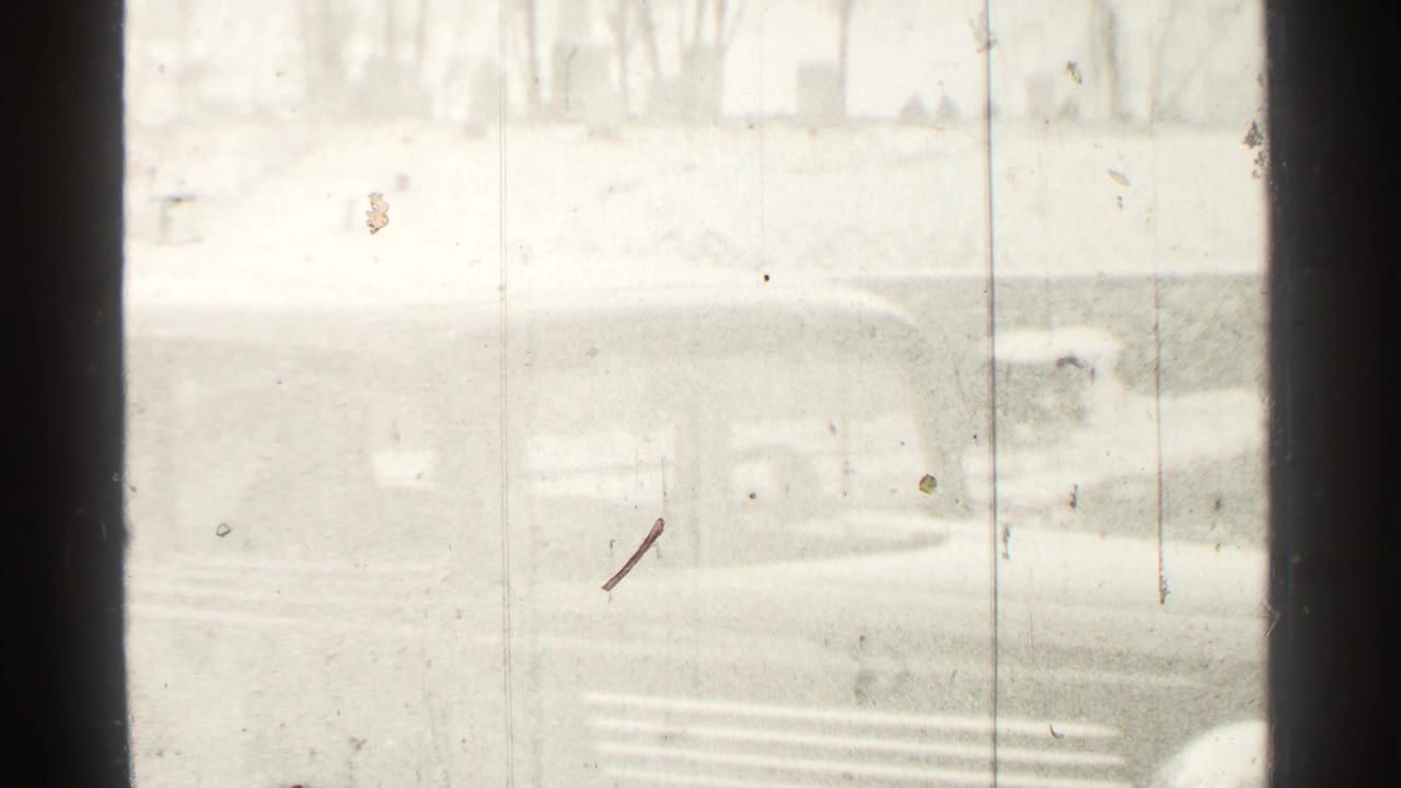 1939 Danielson home-movie frame showing a dark car outside through glass or a window frame, with bright exposure and film scratches.