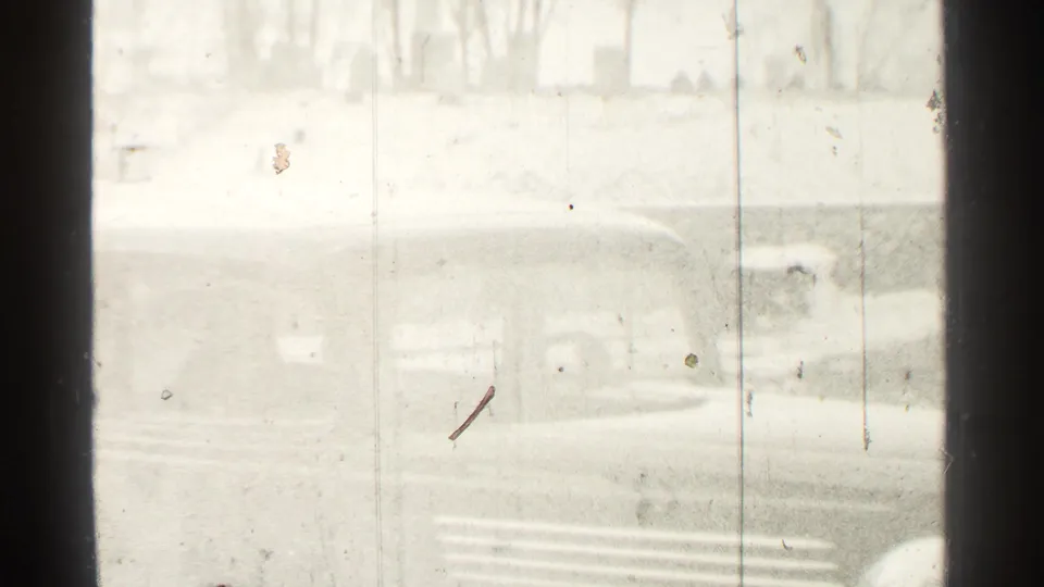 1939 Danielson home-movie frame showing a dark car outside through glass or a window frame, with bright exposure and film scratches.