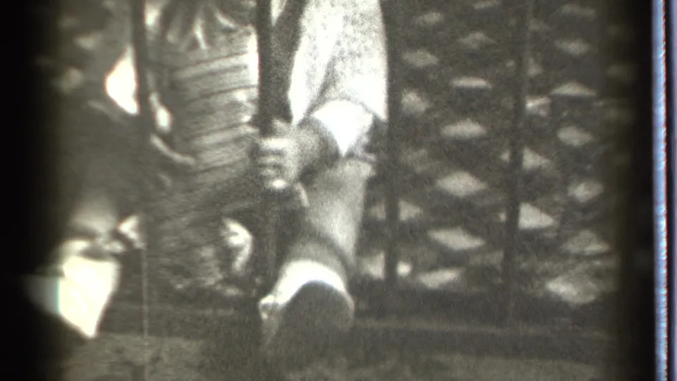 The baby's small hand is wrapped around a dark metal bar, with light clothing and a patterned railing visible in the 1939 Connecticut frame.