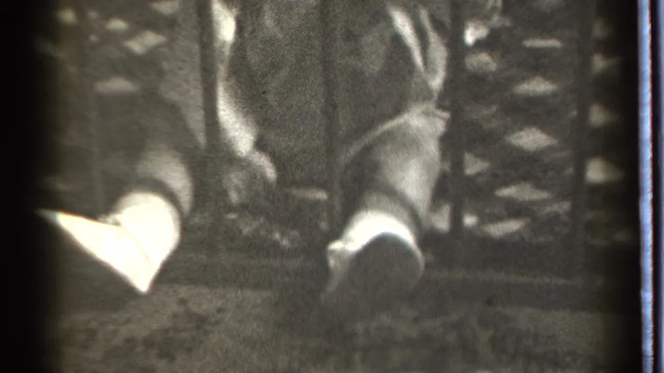 The final frame keeps the child partly obscured behind bars, with light socks and fabric visible in the dim 8mm scene.