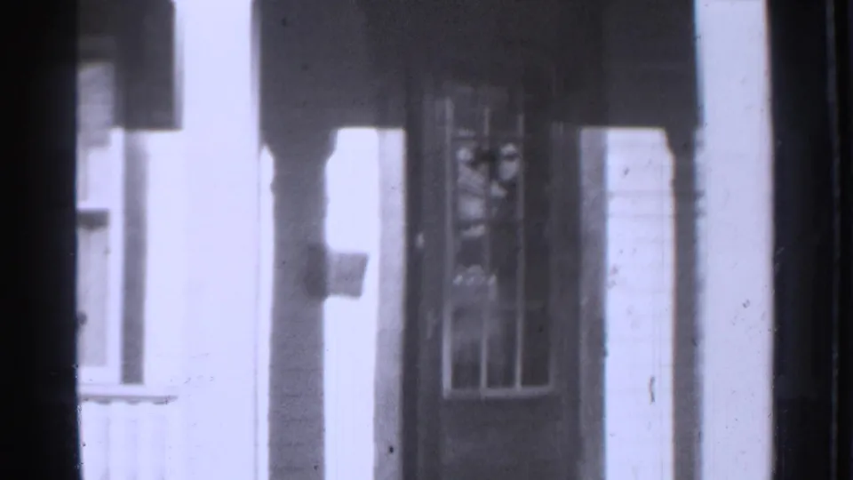 1939 Danielson home-movie frame showing a house porch, doorway, window, columns, and dark film-frame edges.