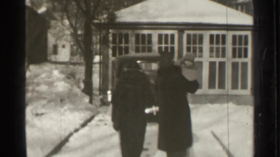 The adults continue toward the vintage car, partly obscured by soft focus and film wear in the 1939 Connecticut home-movie frame.