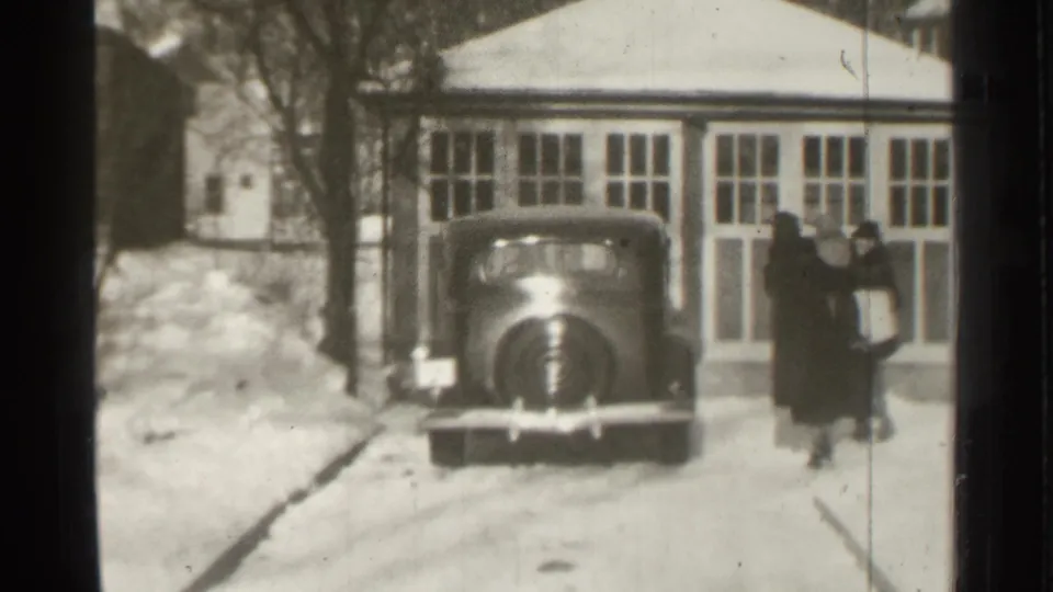 In Danielson, Connecticut in 1939, adults approach a parked car outside a snow-covered garage or house entry.