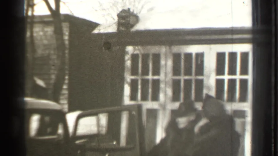 Several adults are visible beside an open automobile door near a snow-covered residential garage in Danielson, Connecticut.