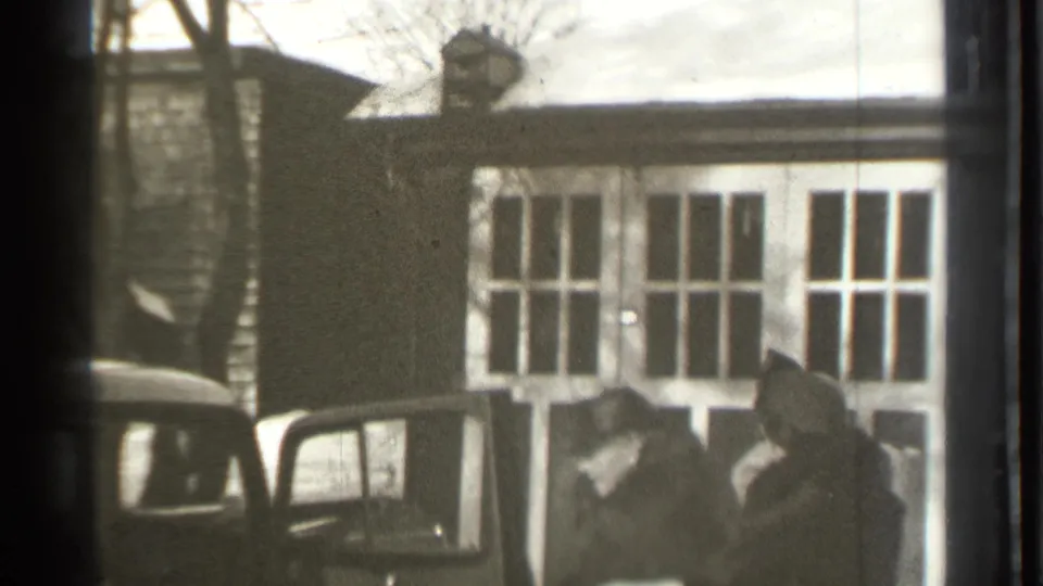 1939 Danielson, Connecticut home-movie frame showing a top-hatted man at an open sedan door near a house facade.