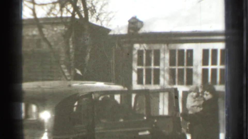1939 Danielson home-movie frame showing the sedan door open as a woman holding an infant stands near the car.