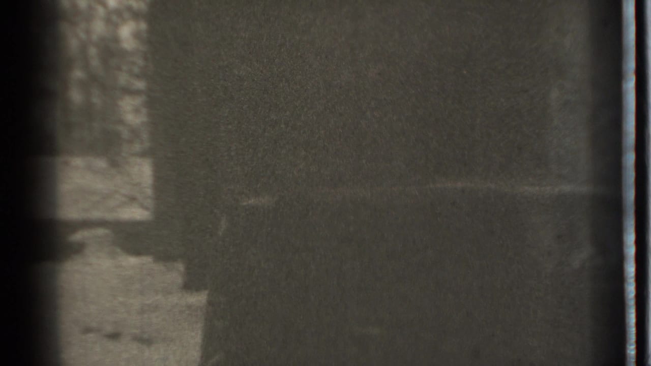 Grainy snowy exterior with bare trees, dark shadow, and film-frame edges.