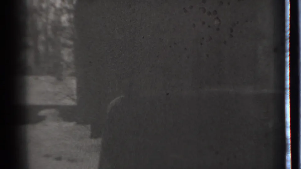 Grainy 1939 8mm view from Danielson with snow and trees partly visible beside a dark obscured surface.