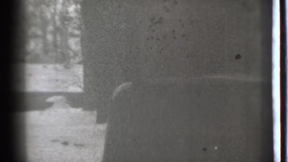 1939 Danielson winter frame with a dark automobile edge, snow on the ground, and bare trees beyond.