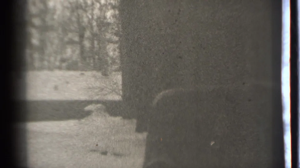 1939 Danielson home-movie frame showing a person in dark winter clothing near a car in snowy terrain.