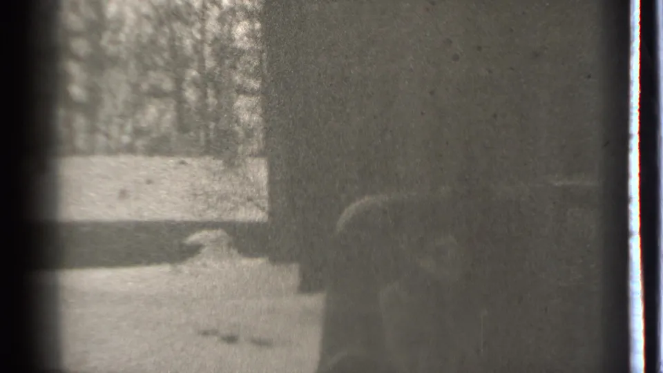 1939 Danielson winter frame with a partly visible person beside a dark car, snowy ground, and bare trees.