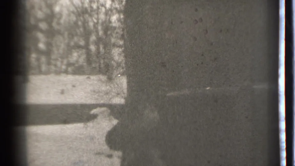 Danielson 1939 home-movie frame with a low, dark human-like shape near a wall and a bright outdoor area at left.