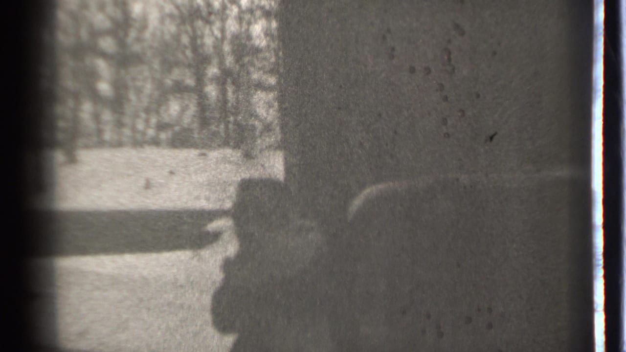 Person and child appear near the right edge, partly obscured by shadow and film wear.