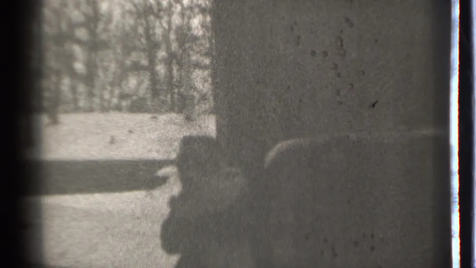 Soft 8mm frame from the Danielson winter scene, with the person carrying a child partly obscured at frame right.