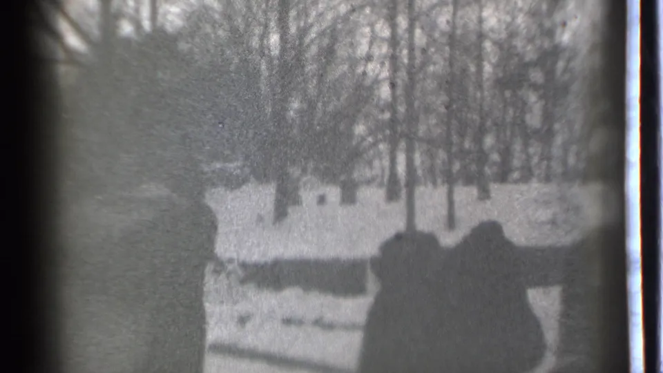 Black-and-white 1939 Danielson frame with two bundled figures in a snowy yard, one arm raised near bare winter trees.