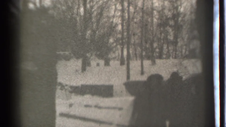Black-and-white 1939 Danielson frame showing a small bundled group in a snowy yard, framed by dark film edges and soft exposure.