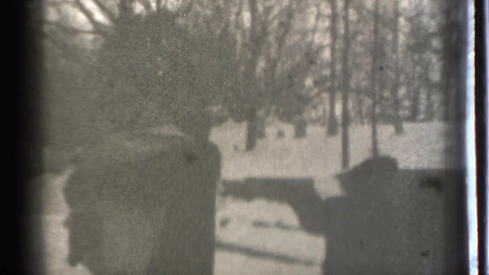 Silhouetted people appear in a snowy Danielson yard, with bare trees and dark hedges or posts visible through grainy 8mm footage.