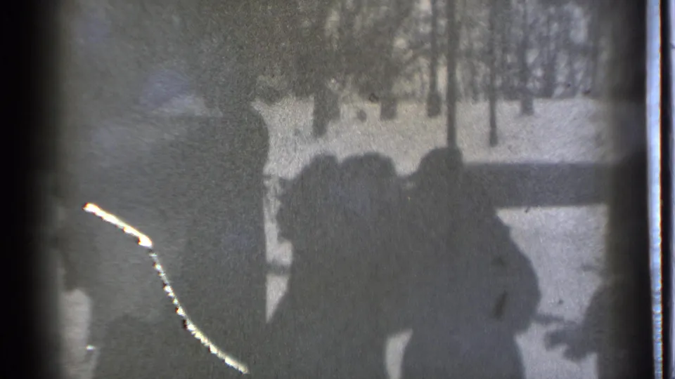 Several silhouetted figures appear near a snowy Danielson yard in 1939, partly obscured by heavy grain, scratches, and the frame edge.