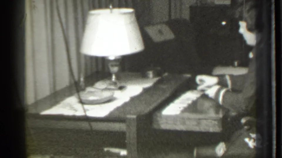 The woman holds or adjusts cards at a lamp-lit table in a private Danielson, Connecticut interior dated 1939.