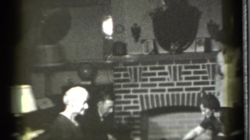 The final 1939 Danielson frame shows multiple adults in a dim living room around a brick fireplace, with lamp light at the side.