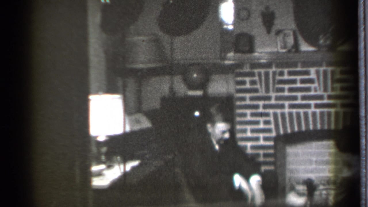 Seated man looking down near a fireplace, with a bright lamp at left.
