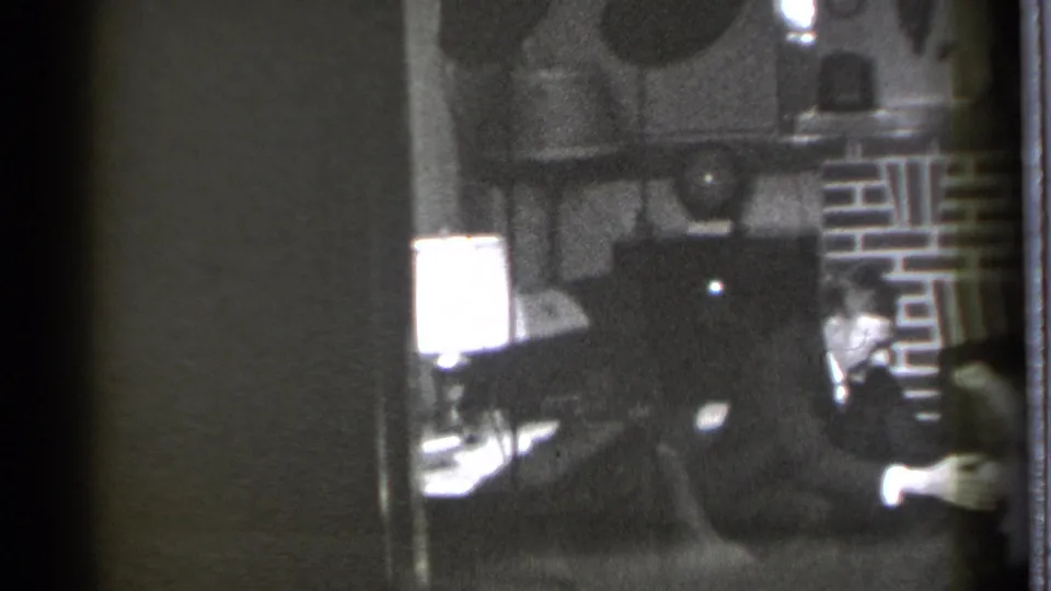 A grainy 1939 Danielson interior frame shows the seated man by the fireplace while the child is partly cropped at the right side.