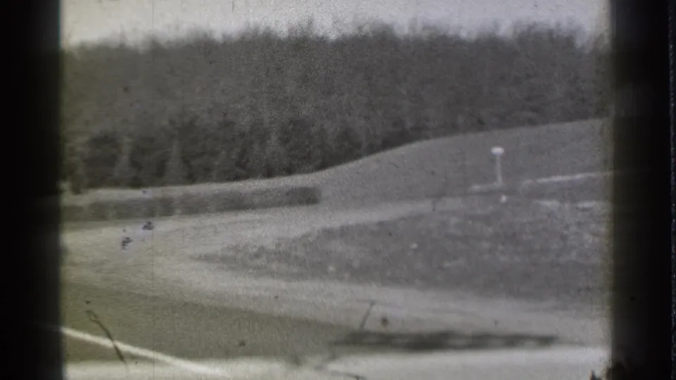 Grainy 1939 Danielson, Connecticut frame showing a road edge, open embankment, low barrier, and tree-covered slope.