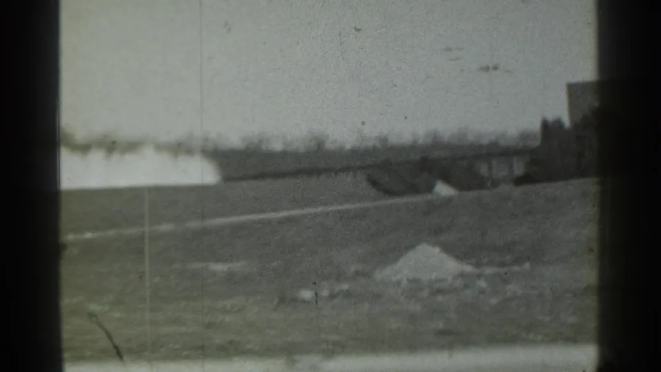 A low industrial building and foreground dirt or gravel pile appear during the 1939 Danielson pan.