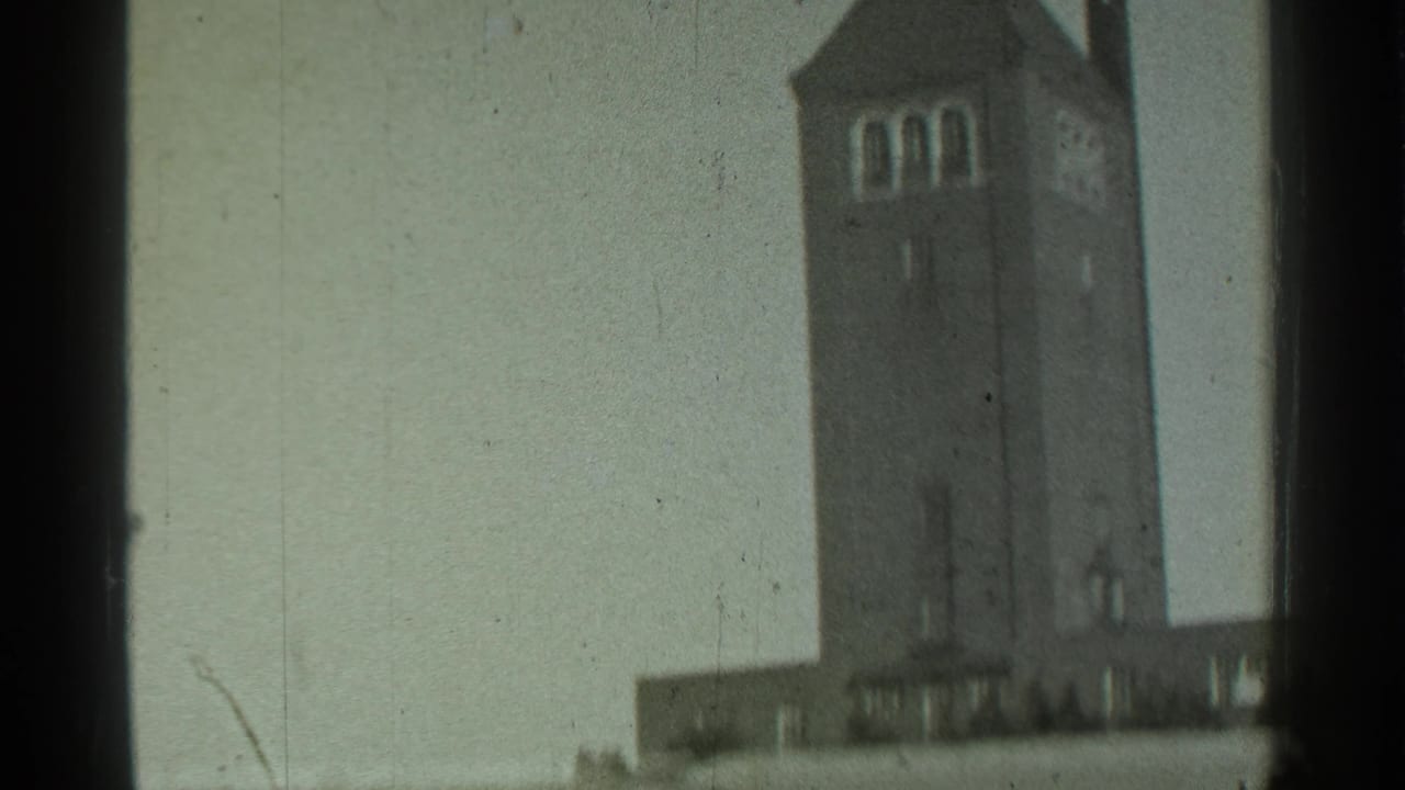 Tall brick tower with arched upper openings against a pale sky.