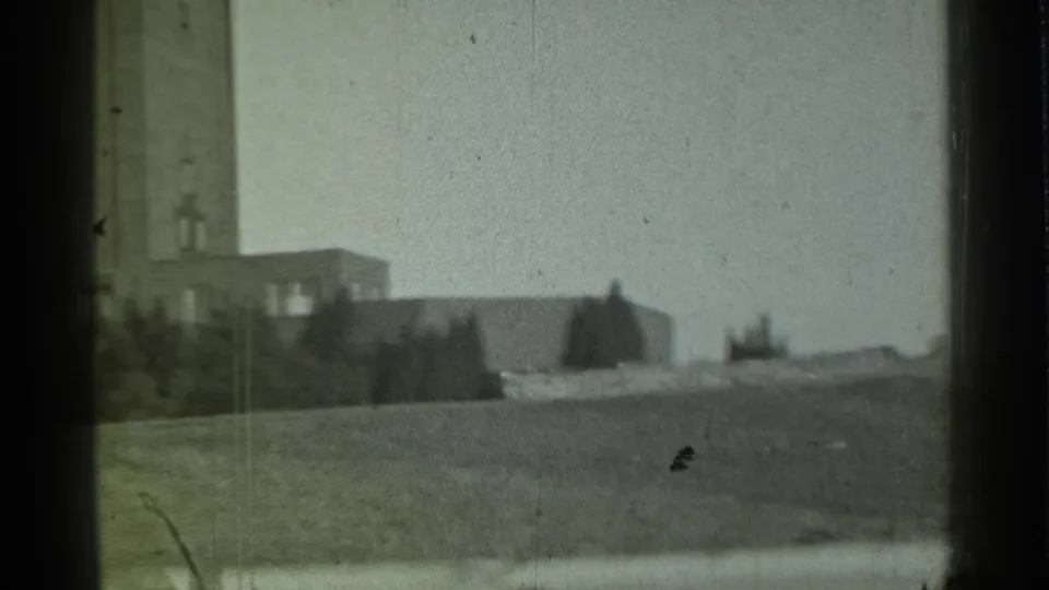 Distant towered building in Danielson, Connecticut, seen across a grassy slope through a dark window frame in 1939 home-movie footage.