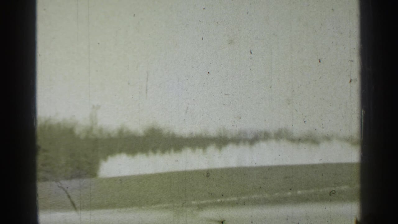 Soft exterior view with a low building or landscape seen through dark film borders.
