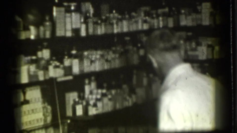 Inside a Danielson, Connecticut pharmacy in 1939, a man in a white shirt appears to work beside shelves packed with medicine bottles.