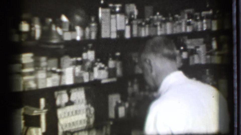 The final frame shows the man turned toward the shelves in the 1939 pharmacy interior, surrounded by bottles, boxes, and counter fixtures.