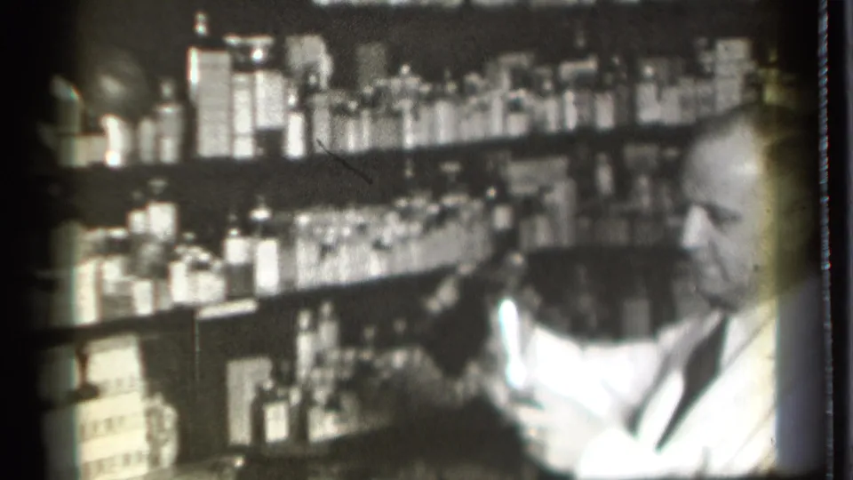 In the final frame, the man holds a container near the crowded pharmacy shelves, consistent with the clip metadata describing liquid handling.