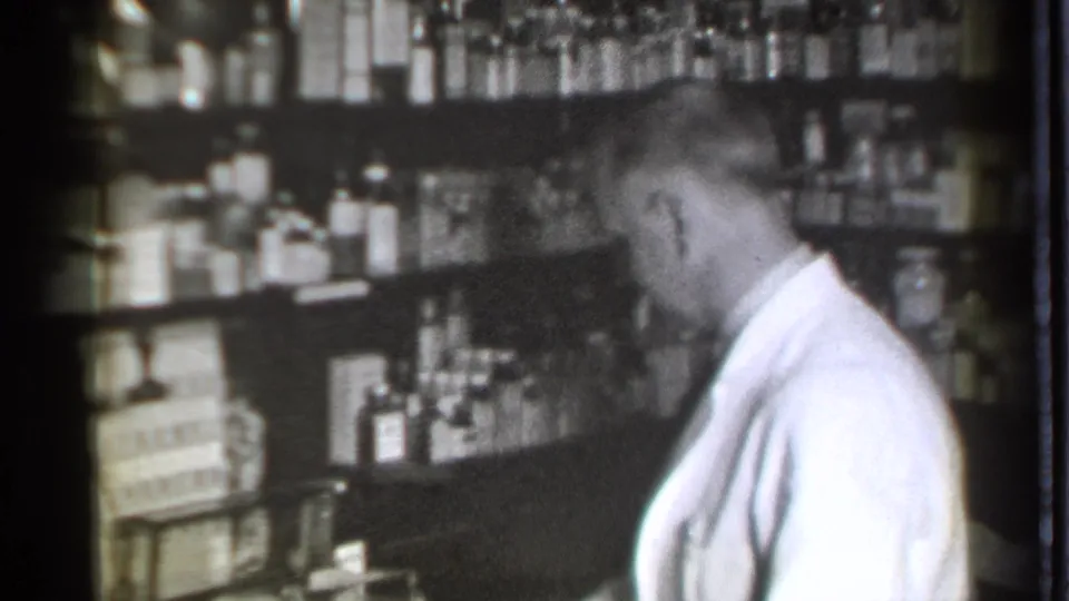 The pharmacist leans over his work area in the Danielson, Connecticut medical shop, with bottles stacked behind him.