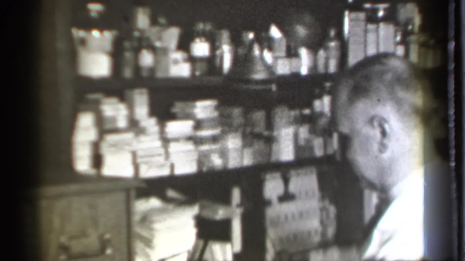 The final frame shows the pharmacist from behind in the 1939 drugstore interior, with stacked boxes, bottles, drawers, and shelving in view.