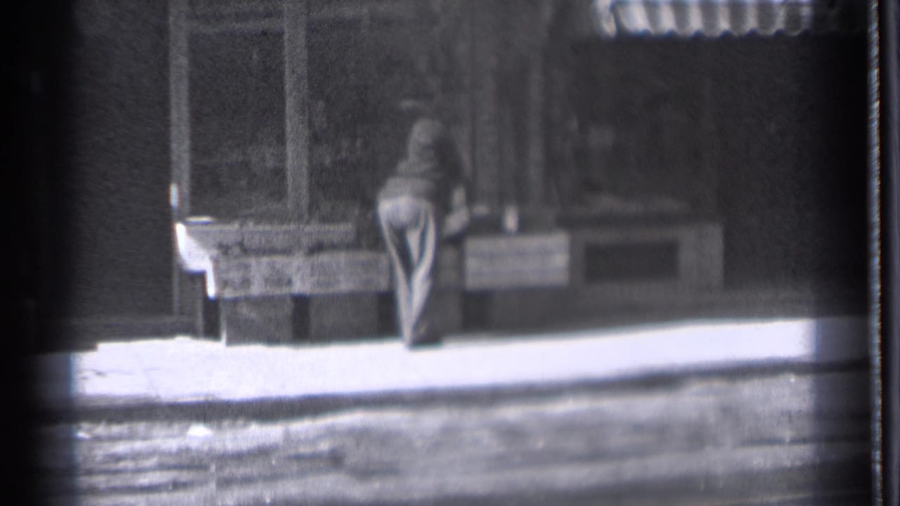 Man faces a sidewalk counter outside a storefront with an awning above.