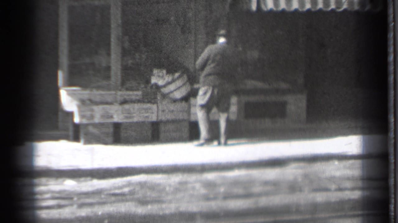 Man in a dark coat bends near wooden crates outside a storefront.