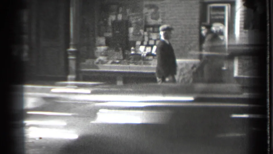 1939 Danielson street frame showing a man walking near storefront displays and a visible Coca-Cola sign.