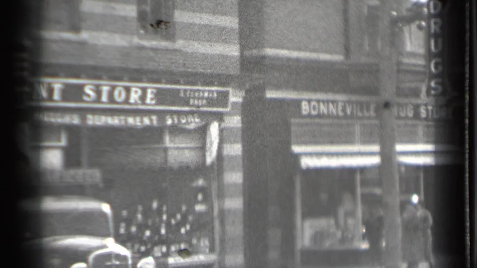 1939 Danielson, Connecticut street view with Bonneville Drug Store signs, a parked vintage car, and pedestrians near shop windows.
